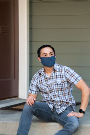 Portrait of confident man wearing mask and plaid shirt smiling and looking away
