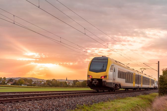 Passenger train traveling at sunrise near a german village