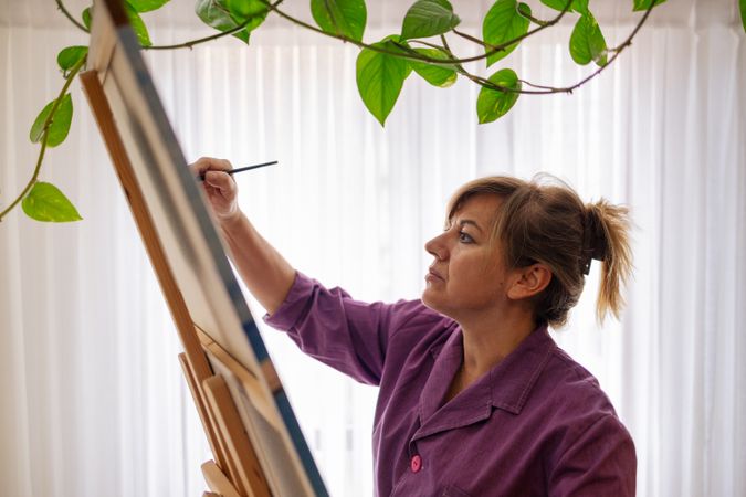 Adult woman painting canvas at home