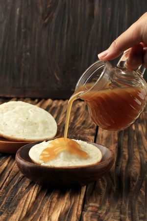 Hand pouring syrup on traditional Indonesian pancake