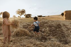 Girl holding a pile of hay looking at her brother