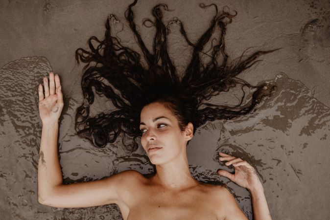 Young woman lying on wet sand