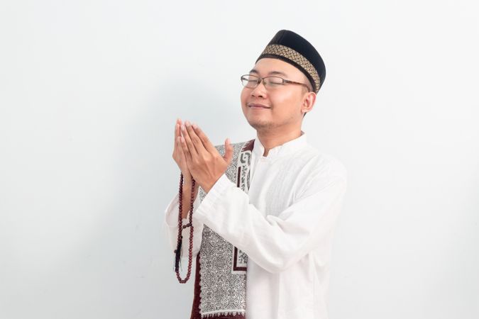 Asian Muslim man doing praying hand pose during Ramadan