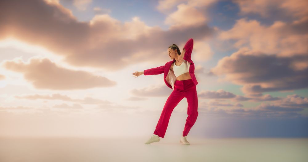 Athletic Woman in Stylish Outfit Dancing Energetically in Studio with Sky Background. Creative Female Performing Contemporary Dance Choreography On Dreamy Set During Virtual Production