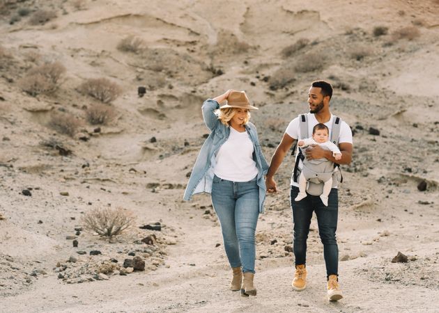 Diverse parents dancing while walking with baby
