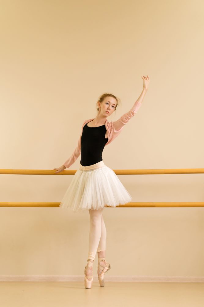 A poised ballerina stretches her arm