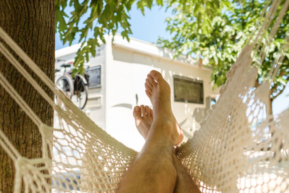 Anonymous male traveler chilling in hammock in countryside