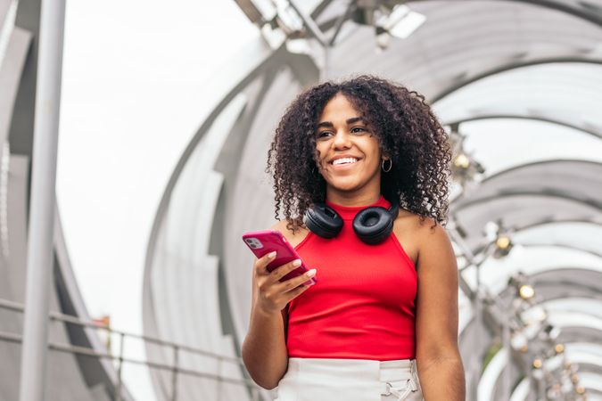 Portrait of a woman with afro hair enjoying in the city using smartphone