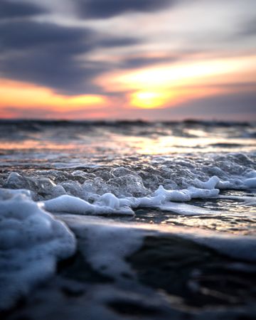 Macro photography of ocean waves crashing on shore during sunrise