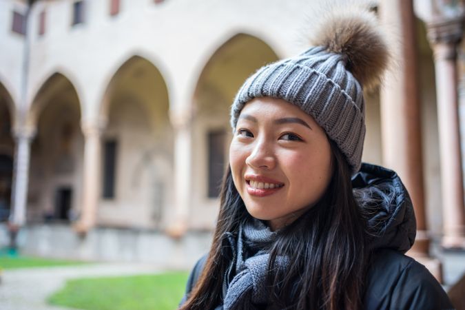 Young Asian female on vacation in warm clothing having excursion at historical temple