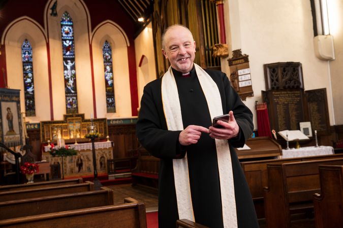 Vicar with phone in parish