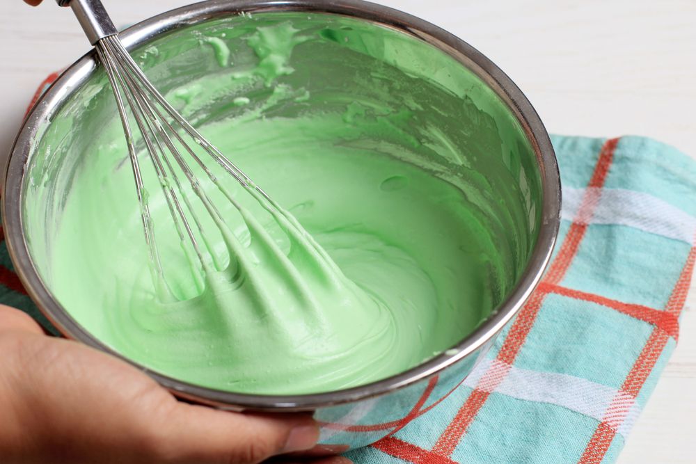 Whisk Green Batter on Stainless Bowl. Woman Hand Hold the Bowl, Cooking or Baking Process