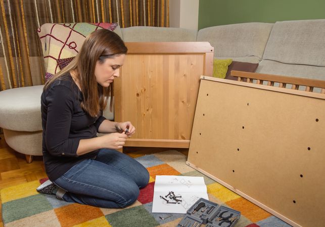 Woman reading instructions to assemble furniture