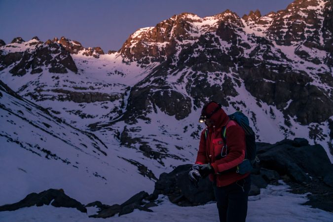 Mountaineer with flashlight standing at mountain cliff