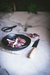 Garlic cloves in peel in bowl with knife