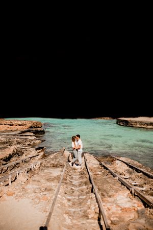 Amorous couple hugging on coastal pier