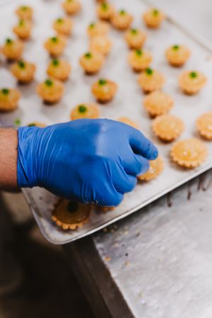 Crop cook decorating pastry with nuts