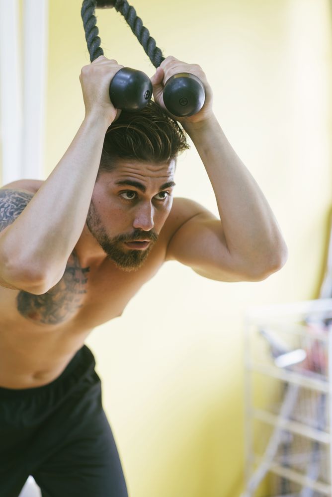 Tattooed male in gym working out his arms