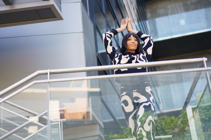 Woman standing on glass staircase with arms up