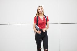 Happy young woman with blonde streaks in her hair holding a textbook