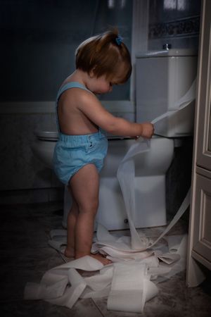 Toddler pulling toilet paper in the bathroom