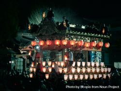 Japanese style structure decorate with light lanterns surrounded by people at nighttime 5kwOG5