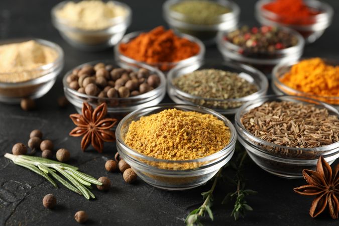 Glass bowls full of spices on dark table