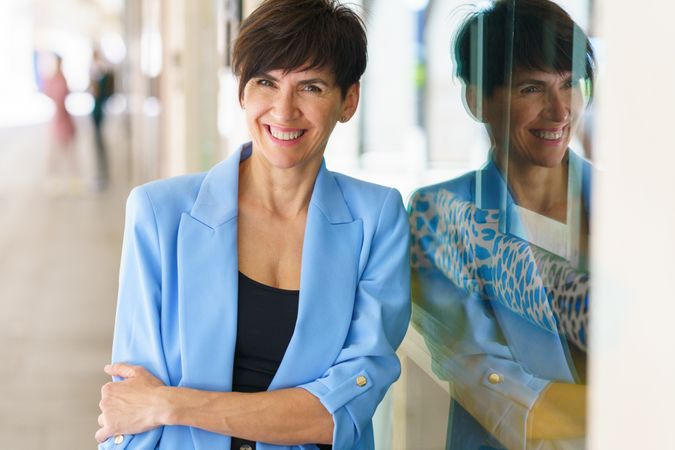 Smiling professional woman leaning on shop window outside