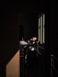 Slender ballerina stretching legs on barre in dark room
