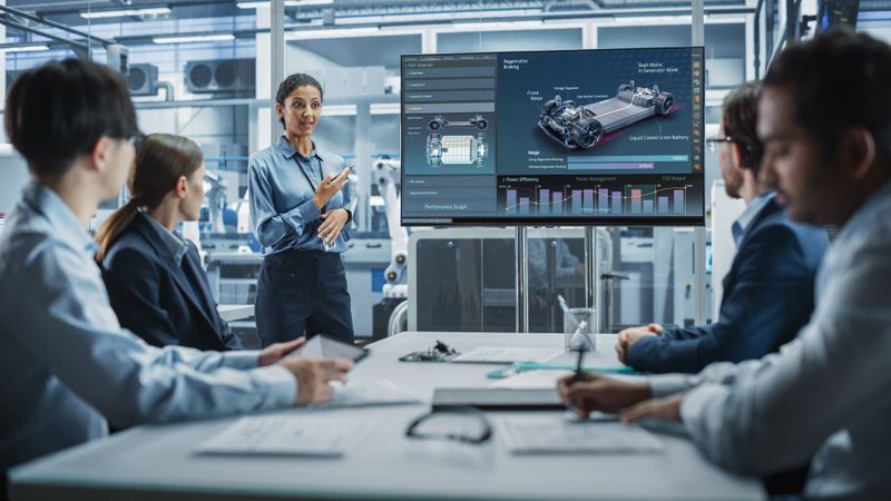 Woman leading group of designers in meeting room with screen