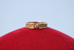 Man's diamond ring resting on red pillow