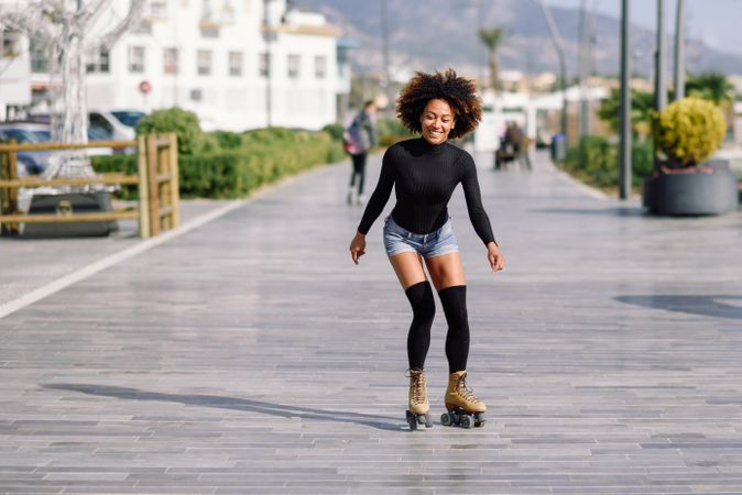 Smiling woman with afro roller skating outside