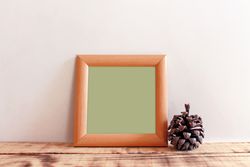 Plain square wooden picture frame with green interior leaning against wall mockup