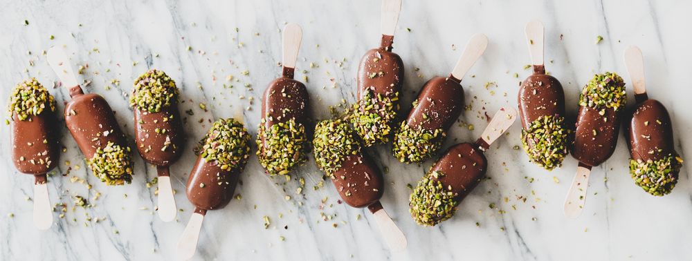 Ice cream chocolate pistachio popsicles, light background, top view, wide composition