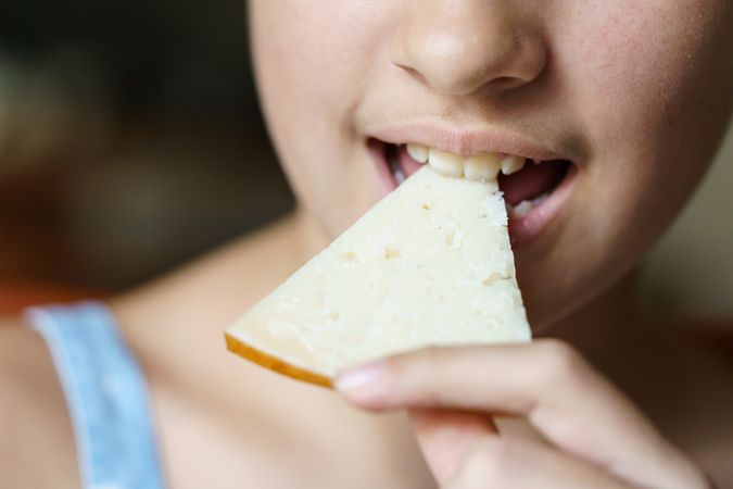 Unrecognizable girl eating delicious cheese slice