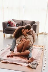 Multiethnic couple hugging on floor at home