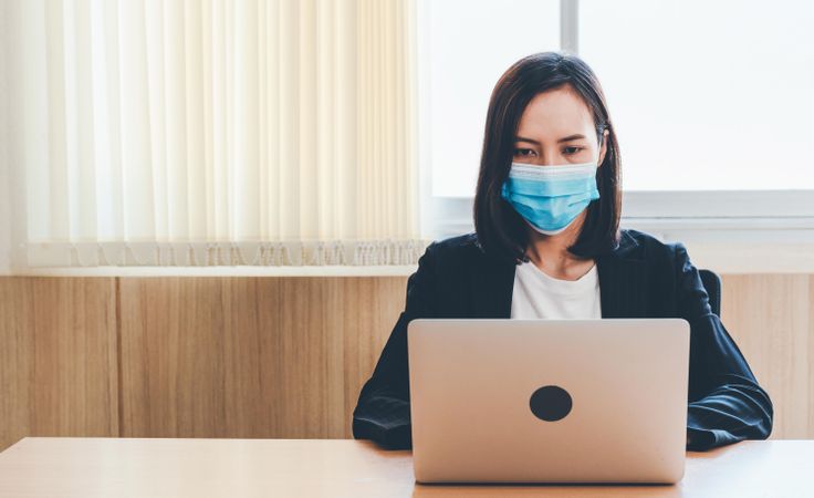 Female doctor in office taking notes on laptop