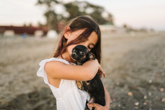 Girl with little dog on sandy beach
