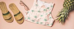 Sandals, glasses, bikini top, pineapple on pink background, wide composition
