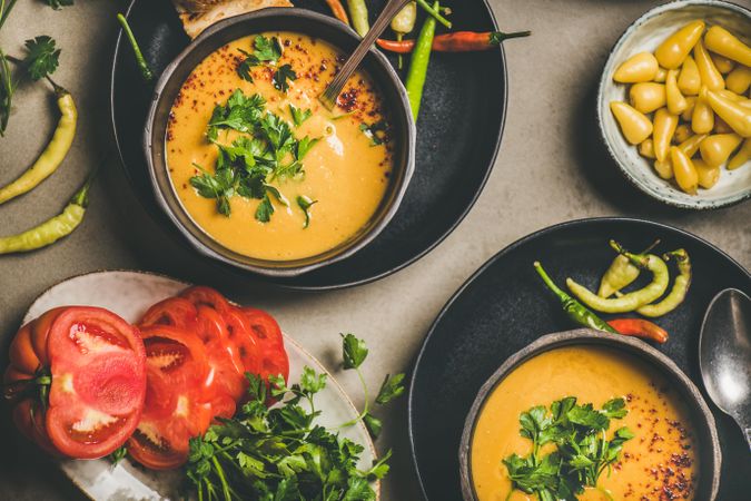 Yellow lentil soup bowls, vegetable garnishes, top view