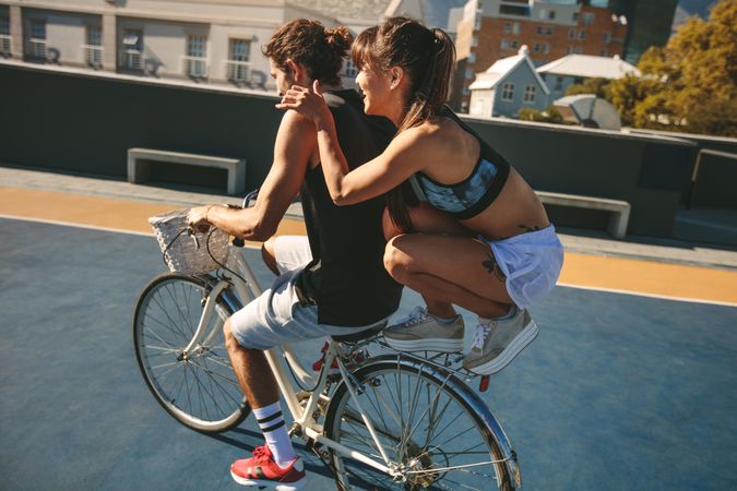 Man riding bicycle with woman friend sitting on back