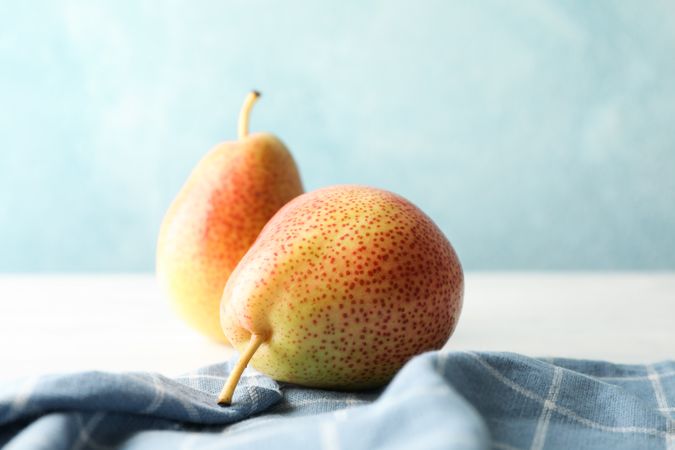 Pears and towel on table against light blue background