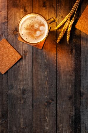 Top view of beer on wooden table with wheat stalk with copy space
