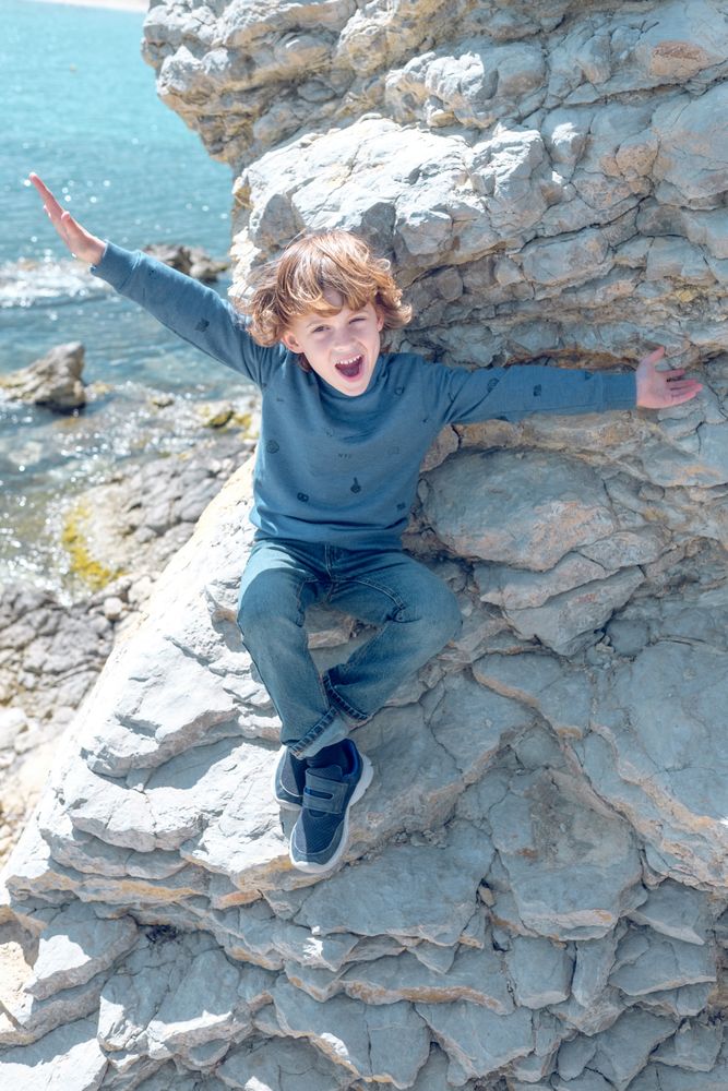 Delighted boy on cliff near sea
