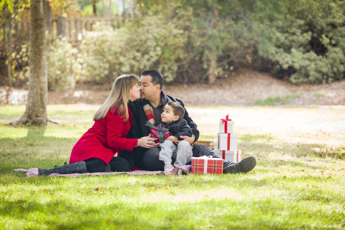 Family Enjoying Christmas Gifts in the Park Together