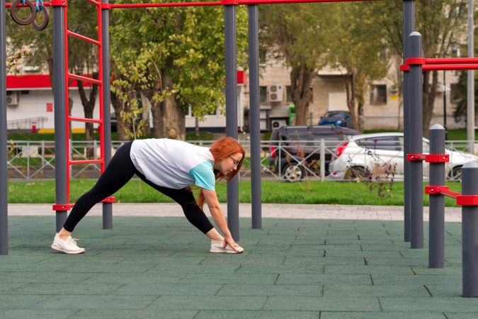 Woman bending forward while holding foot during outdoor stretching session