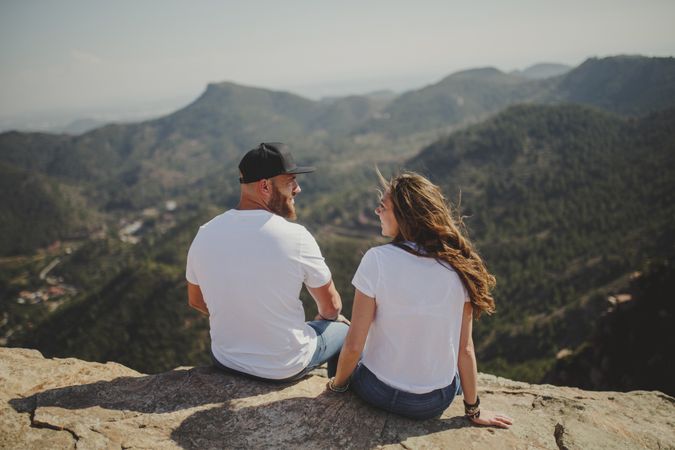 Happy couple talking while sitting at mountain cliff