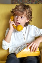 Pensive boy talking on retro telephone in room