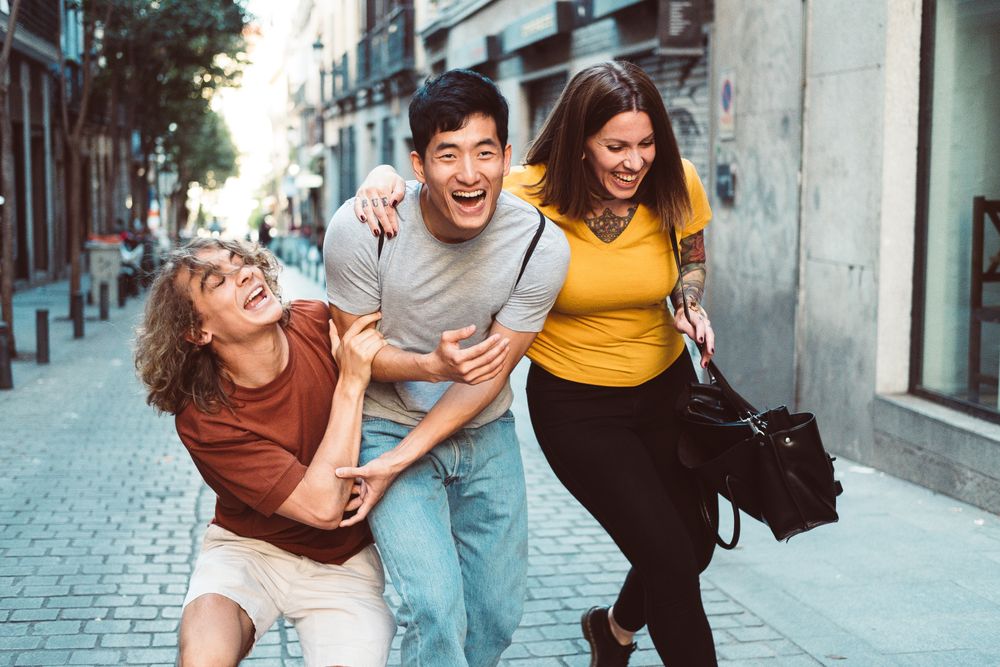 Funny multiracial friends having fun along city street
