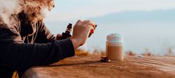 Vaper puffing smoke and taking shot of coffee